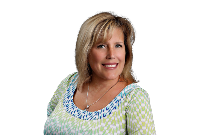 Smiling woman with blonde hair wearing a patterned top against a plain background.